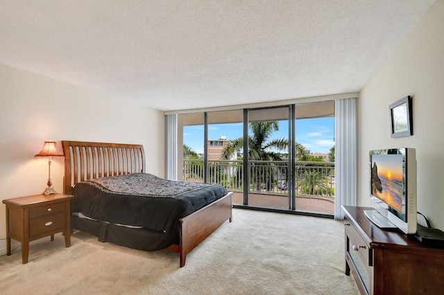 carpeted bedroom with a textured ceiling, expansive windows, and access to exterior