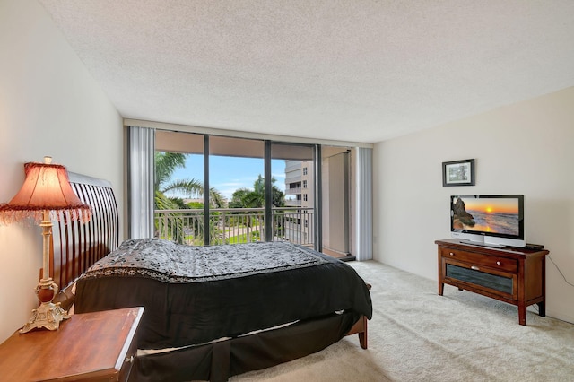 carpeted bedroom featuring expansive windows, a textured ceiling, and access to exterior