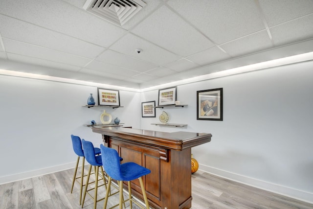 bar featuring light hardwood / wood-style flooring and a paneled ceiling