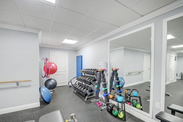 exercise room with a paneled ceiling, carpet, and crown molding