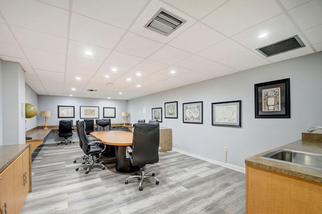 office space featuring sink, light wood-type flooring, and a drop ceiling