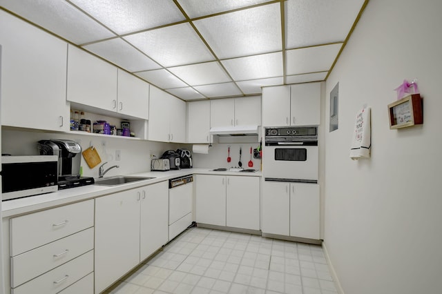 kitchen with a drop ceiling, white cabinets, sink, light tile patterned flooring, and white appliances