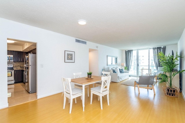 dining area featuring light wood-type flooring and a textured ceiling