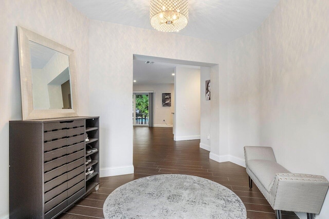 corridor featuring baseboards, a chandelier, and dark wood-style flooring