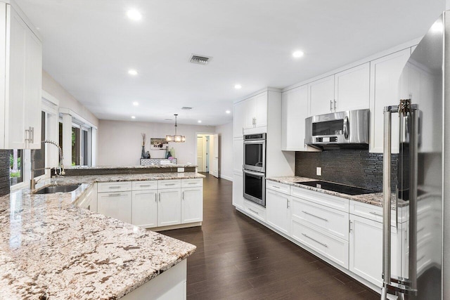 kitchen featuring dark wood-style flooring, visible vents, appliances with stainless steel finishes, a sink, and a peninsula