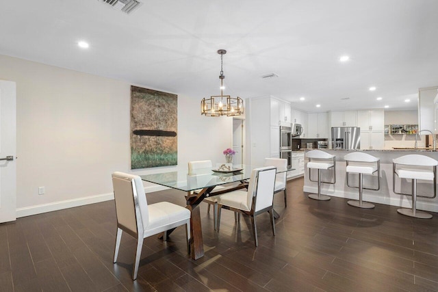 dining area with sink, a notable chandelier, and wood-type flooring