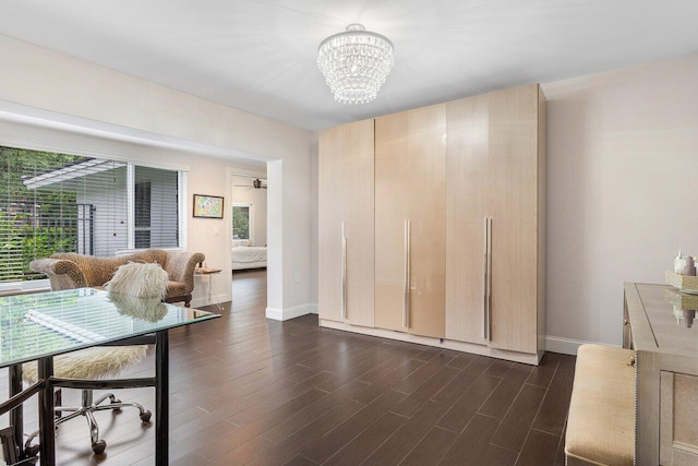 interior space featuring dark wood-type flooring, a chandelier, and baseboards