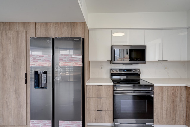 kitchen with decorative backsplash, white cabinetry, stainless steel appliances, and light brown cabinetry