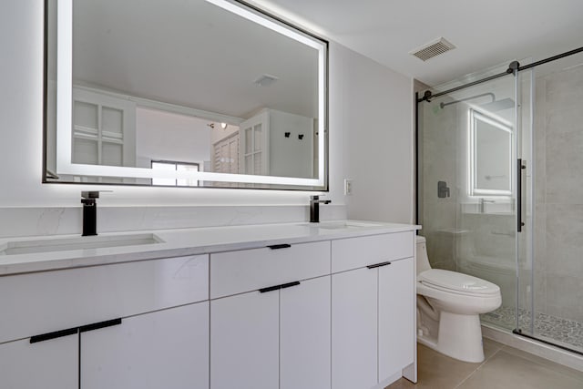 bathroom with a shower with door, vanity, toilet, and tile patterned flooring