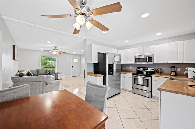 kitchen featuring light tile patterned floors, appliances with stainless steel finishes, sink, white cabinetry, and ceiling fan