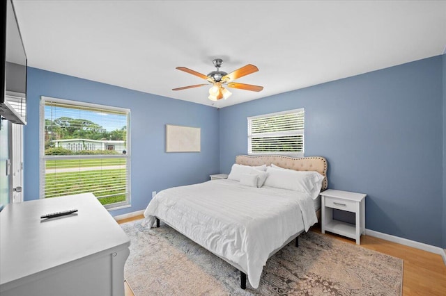 bedroom with ceiling fan, multiple windows, and light hardwood / wood-style floors