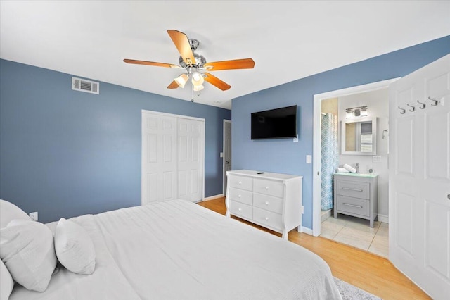 bedroom featuring ensuite bath, a closet, ceiling fan, and light hardwood / wood-style floors