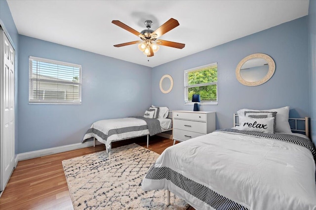 bedroom with multiple windows, ceiling fan, hardwood / wood-style floors, and a closet