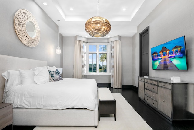 bedroom with a tray ceiling and dark wood-type flooring