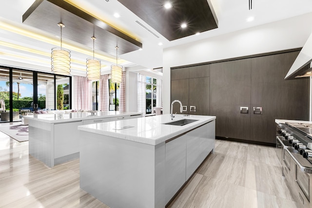 kitchen with sink, a kitchen island with sink, light tile patterned floors, and light stone countertops