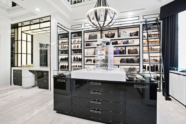 walk in closet with a raised ceiling, a chandelier, and light colored carpet