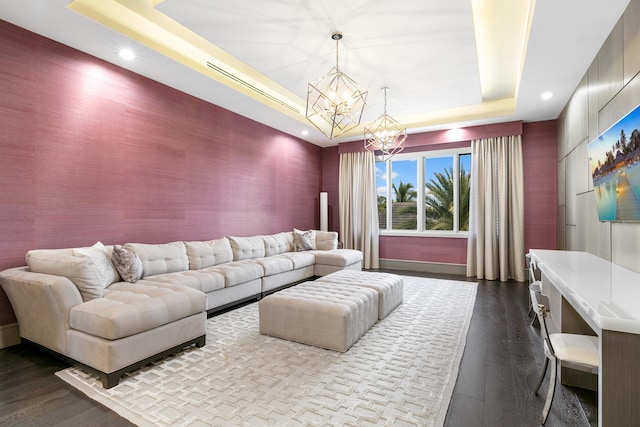 living room with a raised ceiling, dark hardwood / wood-style floors, and a chandelier