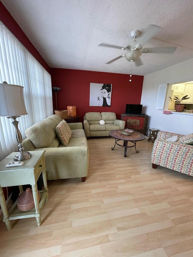 living room with ceiling fan, light hardwood / wood-style flooring, and a textured ceiling