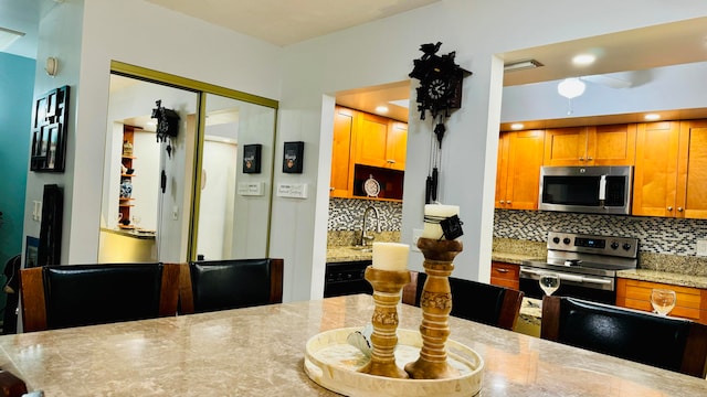 kitchen with decorative backsplash, stainless steel appliances, and light stone counters