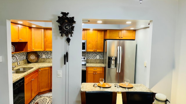 kitchen featuring backsplash, stainless steel appliances, light stone counters, and sink