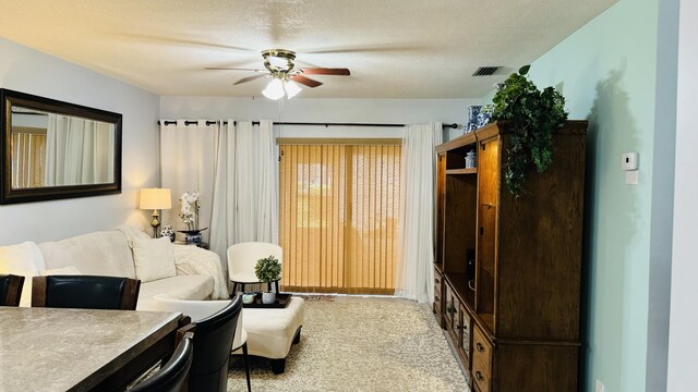 living room with a textured ceiling, light carpet, and ceiling fan