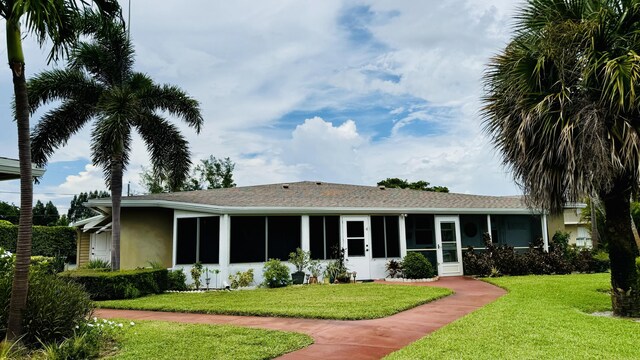 view of front of home featuring a sunroom and a front lawn