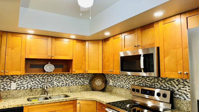 kitchen with light stone counters, appliances with stainless steel finishes, sink, and tasteful backsplash