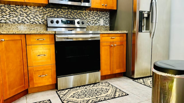 kitchen featuring light stone countertops, backsplash, appliances with stainless steel finishes, and light tile patterned floors