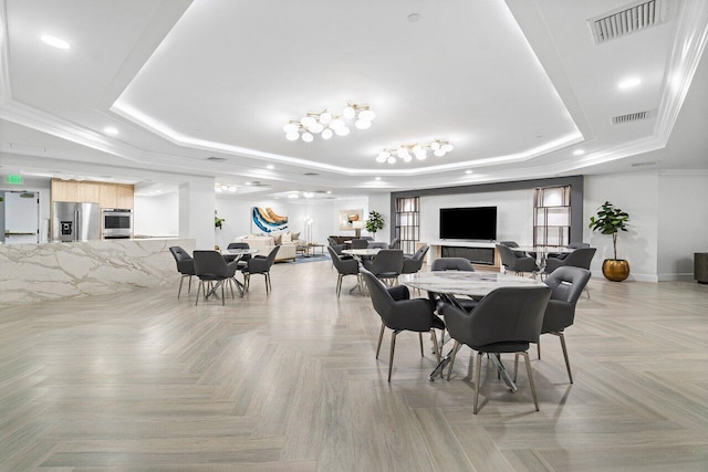 dining area featuring light parquet floors, crown molding, and a tray ceiling