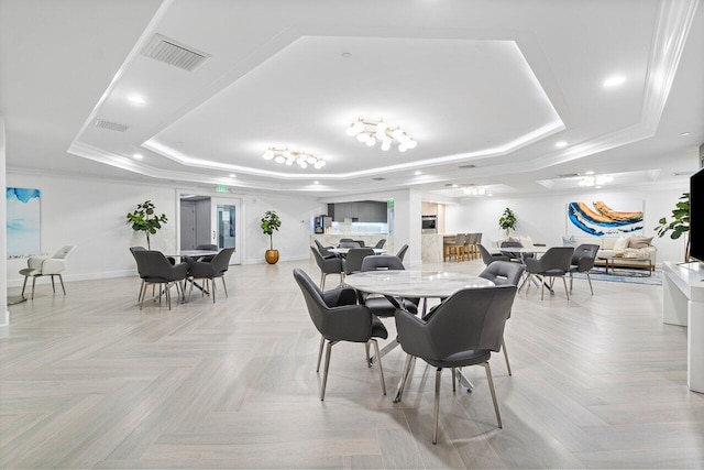 dining space featuring ornamental molding, a tray ceiling, and light parquet flooring