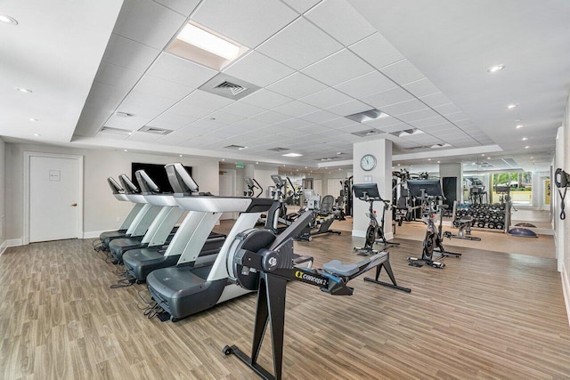 exercise room featuring a paneled ceiling and light hardwood / wood-style floors