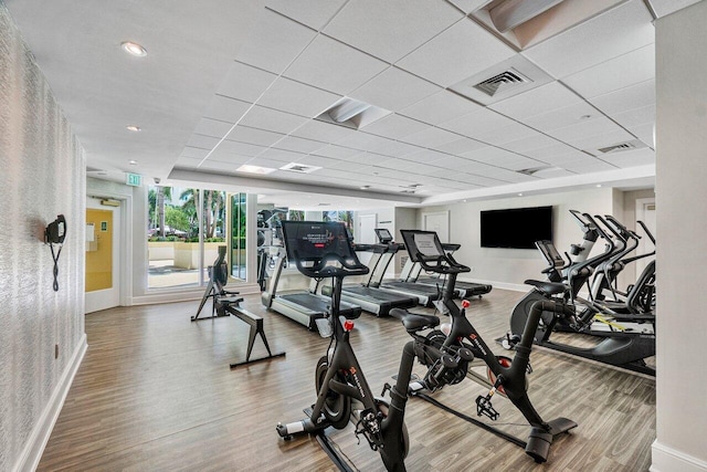 workout area with a paneled ceiling and hardwood / wood-style flooring