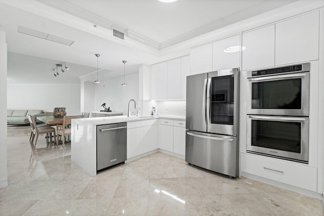 kitchen with white cabinets, stainless steel appliances, kitchen peninsula, pendant lighting, and ornamental molding