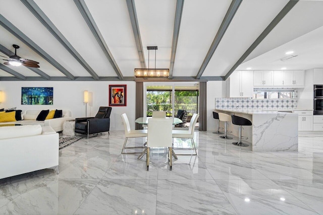 dining room featuring ceiling fan with notable chandelier and lofted ceiling with beams