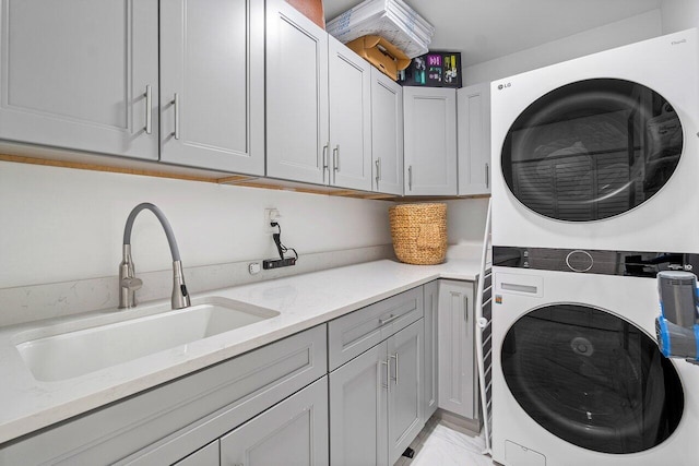 laundry area with stacked washer and clothes dryer, sink, and cabinets