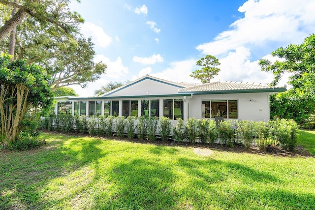 back of house with a sunroom and a lawn