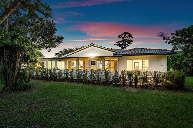 back house at dusk featuring a yard