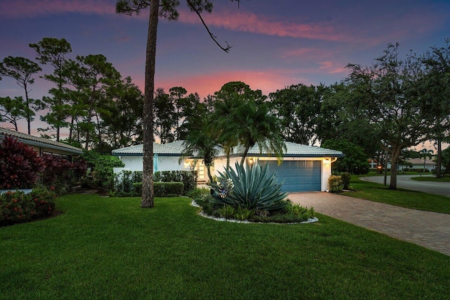 ranch-style house with a garage and a lawn