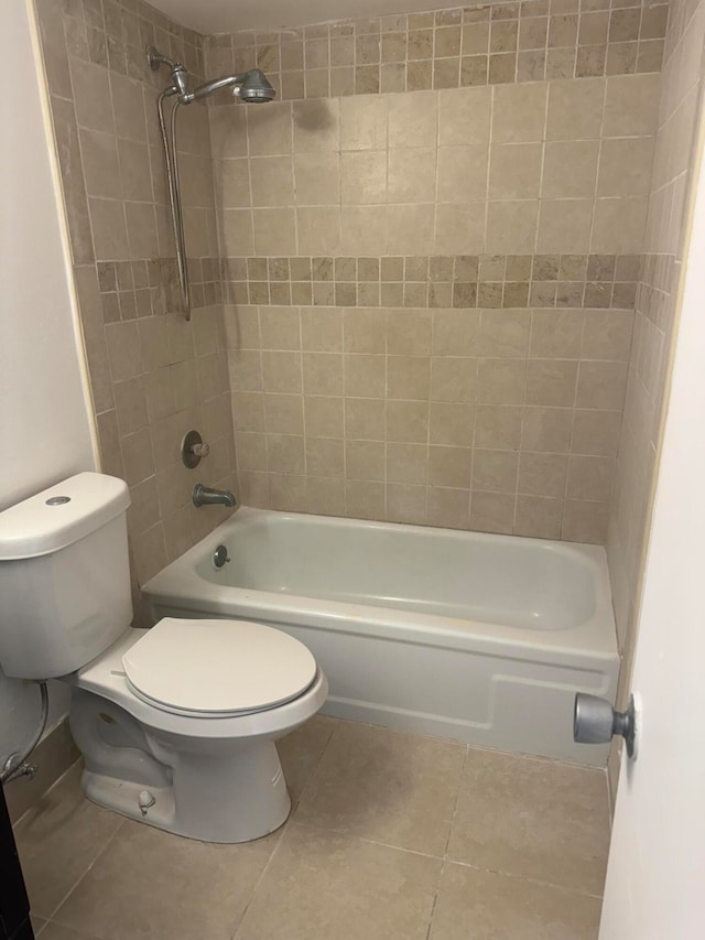 bathroom with tile patterned flooring, toilet, and tiled shower / bath combo