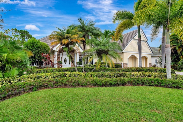 view of front facade featuring a front yard, a tiled roof, and stucco siding