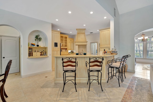 kitchen featuring a kitchen bar, light brown cabinets, light tile patterned floors, kitchen peninsula, and a notable chandelier