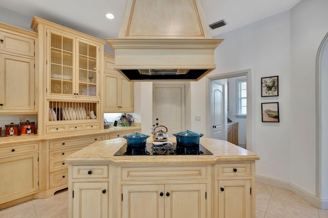 kitchen with visible vents, a center island, custom exhaust hood, black electric cooktop, and light countertops