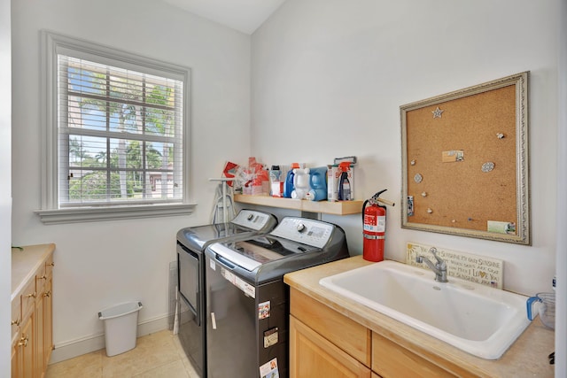 laundry room with light tile patterned floors, a sink, baseboards, cabinet space, and washer and clothes dryer