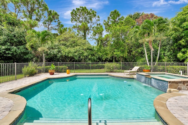 view of swimming pool featuring a pool with connected hot tub and fence