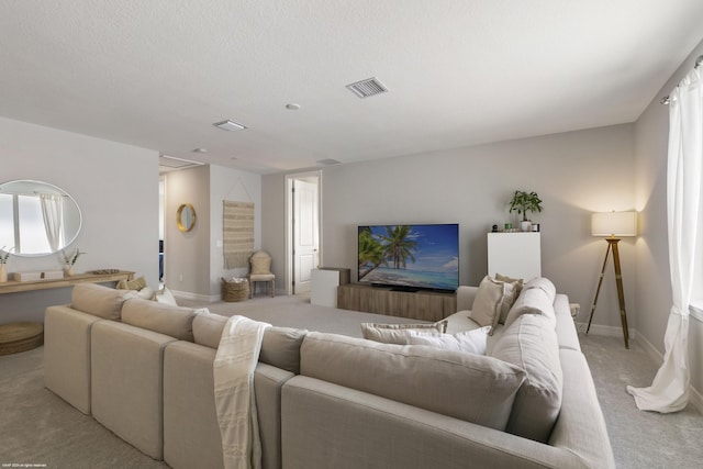 living area featuring light carpet, a textured ceiling, visible vents, and baseboards