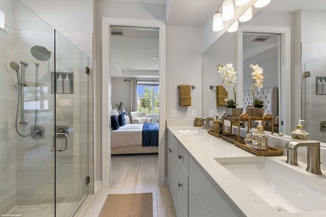 ensuite bathroom featuring connected bathroom, a stall shower, a sink, and double vanity