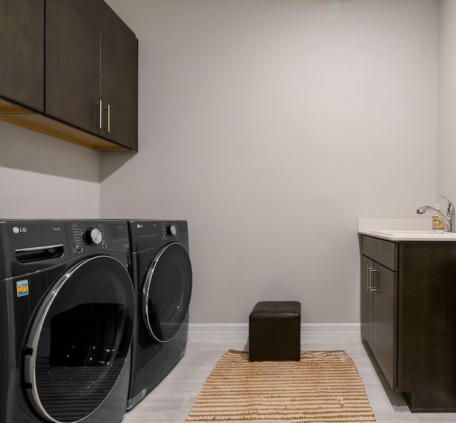 laundry room featuring a sink, washing machine and dryer, cabinet space, and baseboards