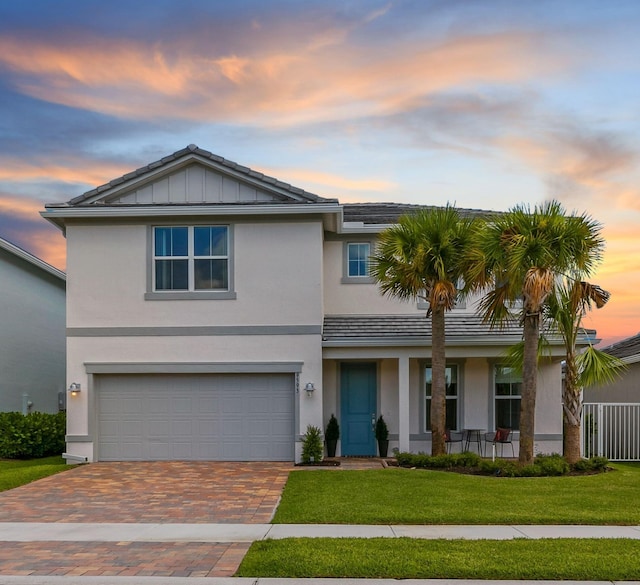 view of front facade featuring decorative driveway, stucco siding, a porch, a front yard, and a garage