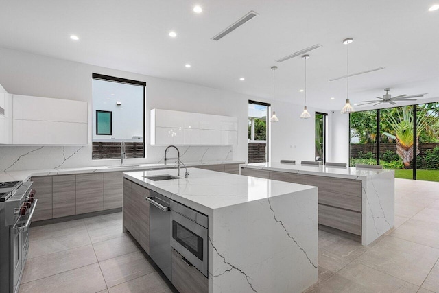 kitchen with a spacious island, decorative backsplash, white cabinetry, and sink