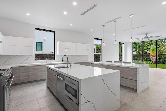kitchen with a sink, decorative backsplash, modern cabinets, a large island, and visible vents